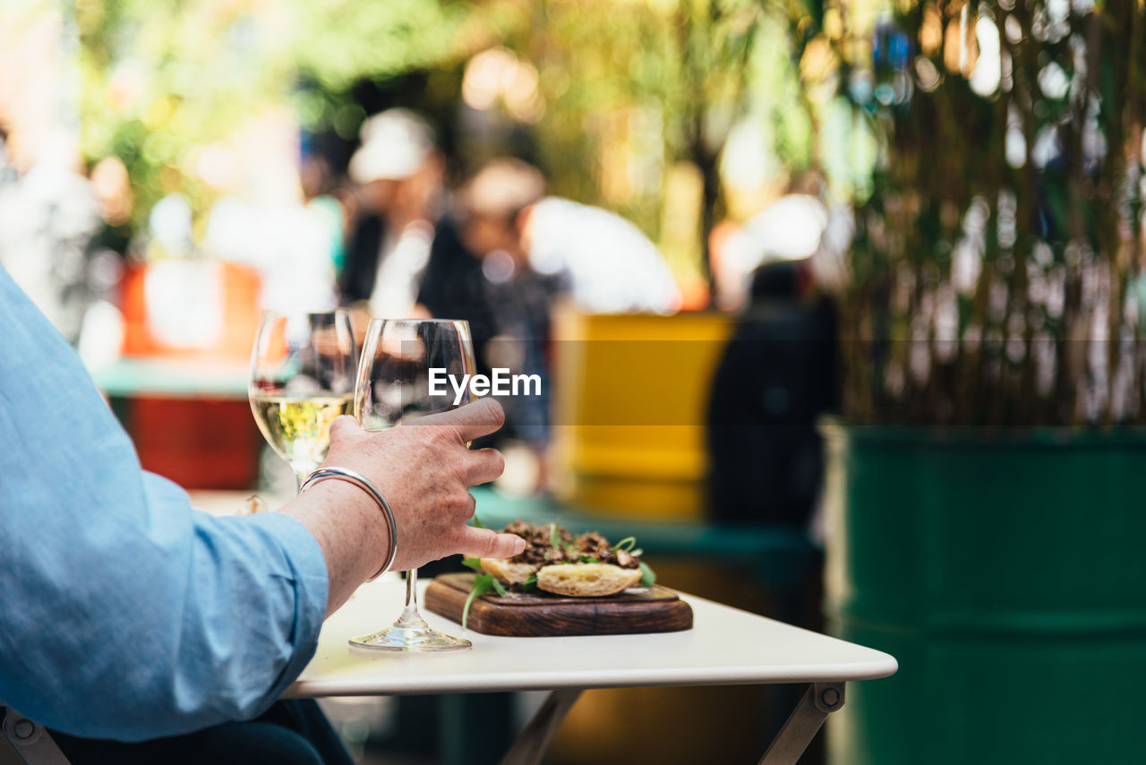 Woman enjoying meal with white wine in a trendy shopping area sitting on a terrace.