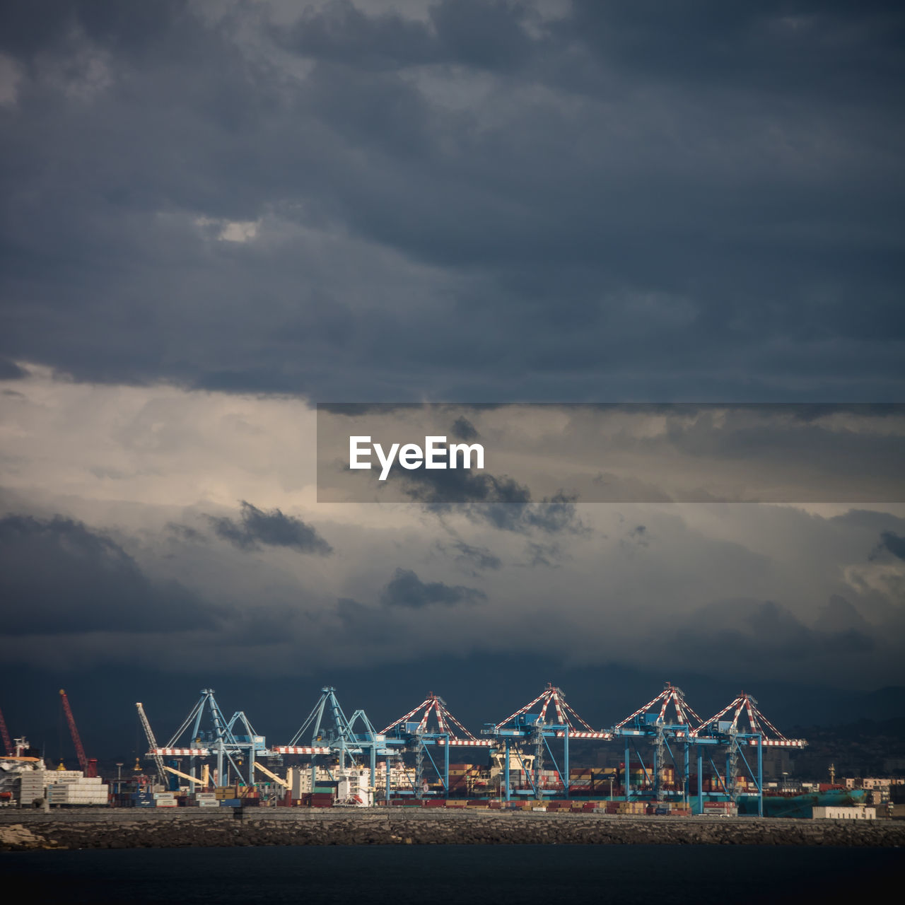 View of cranes at harbor against sky