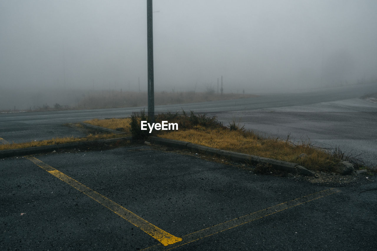 fog, road, morning, mist, no people, transportation, sign, nature, horizon, sky, environment, road marking, street, symbol, haze, marking, wind, wet, water, day, city, outdoors, beauty in nature, asphalt, cold temperature, winter, tranquility, empty road, storm, scenics - nature, overcast, sea, landscape, rain