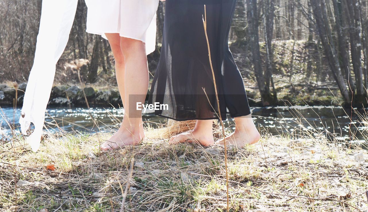 LOW SECTION OF WOMAN STANDING ON SHORE