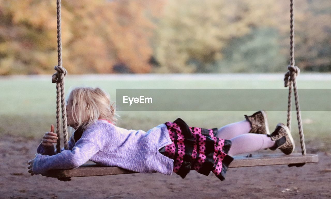 Full length of girl lying on swing at park