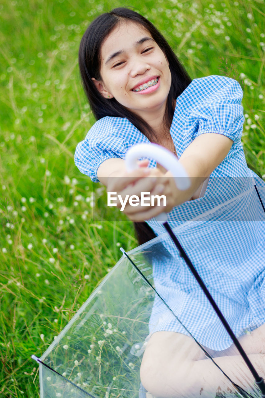 Smiling young woman sitting on field