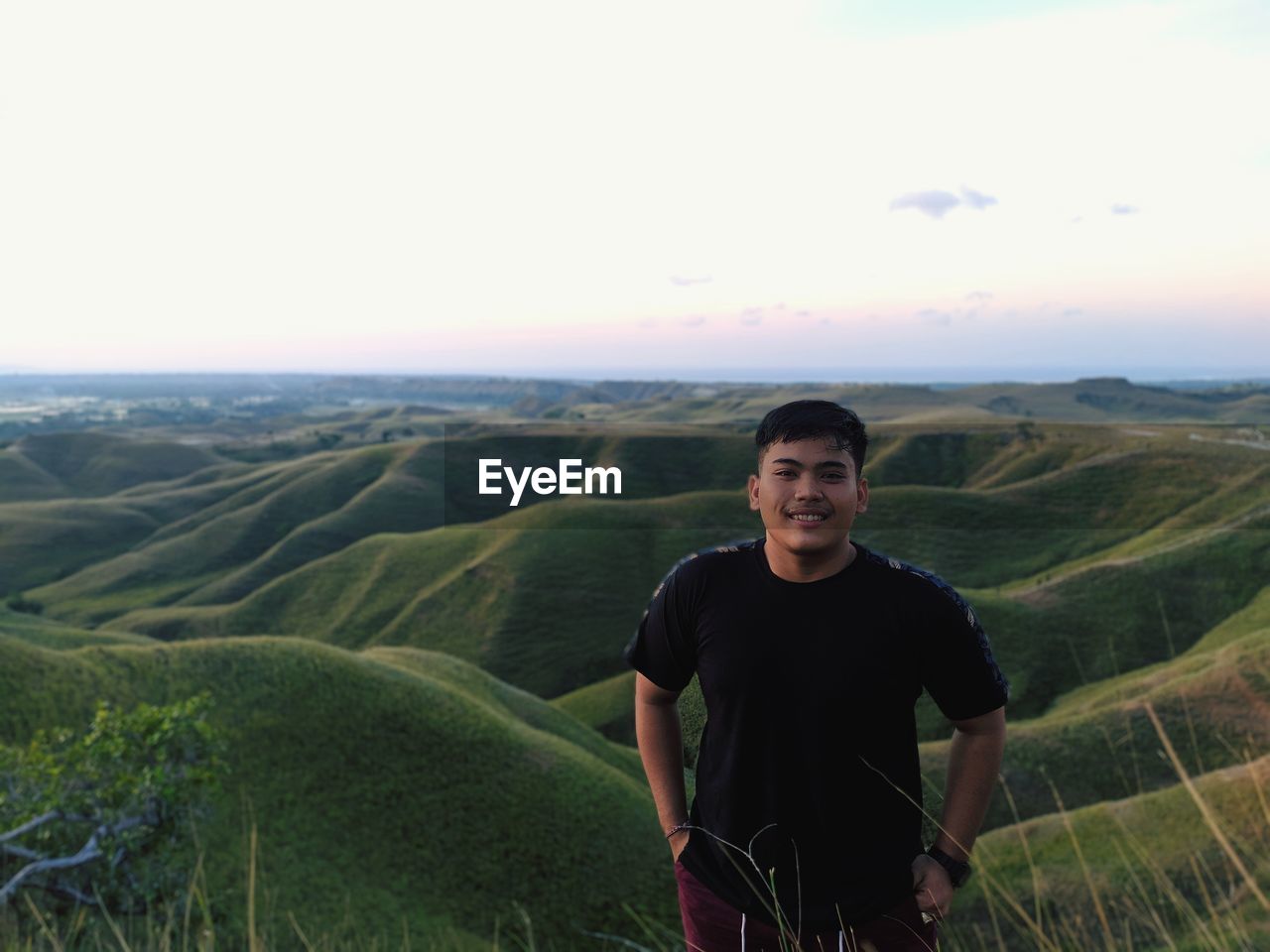 Portrait of smiling man standing on land against sky