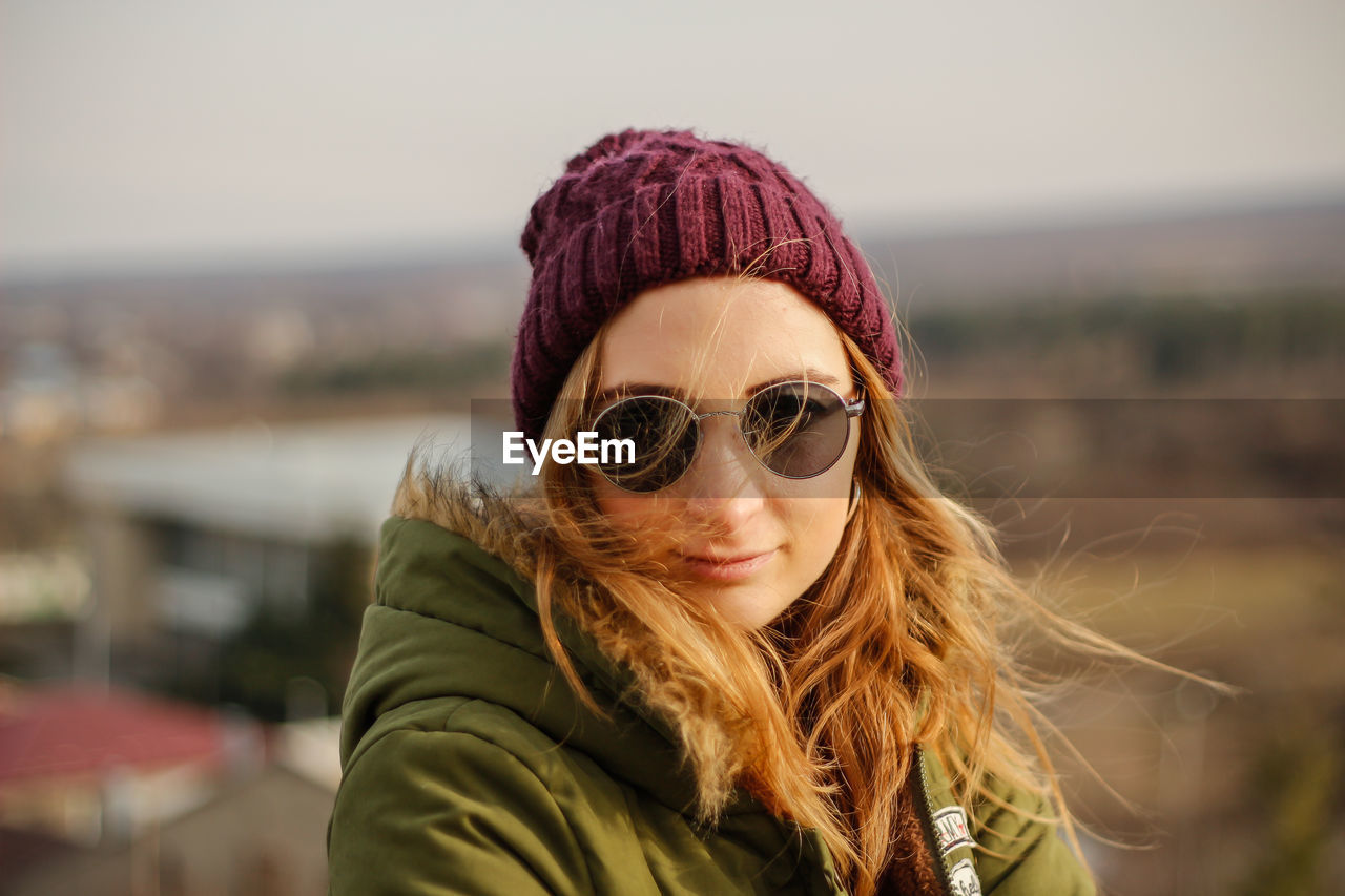 Portrait of young woman in warm clothes wearing sunglasses