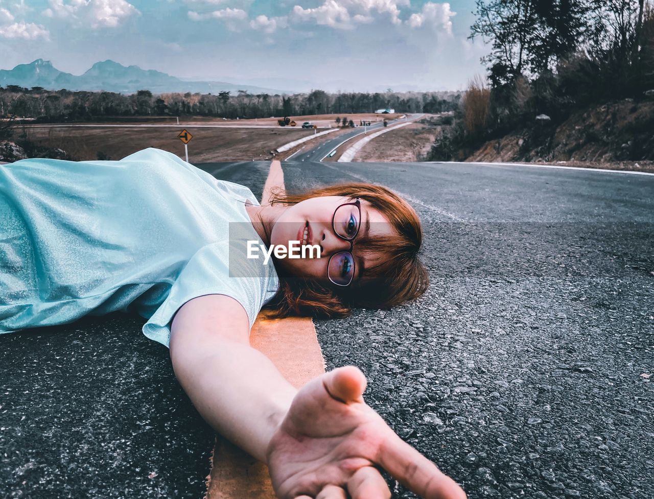 Portrait of young woman lying on road