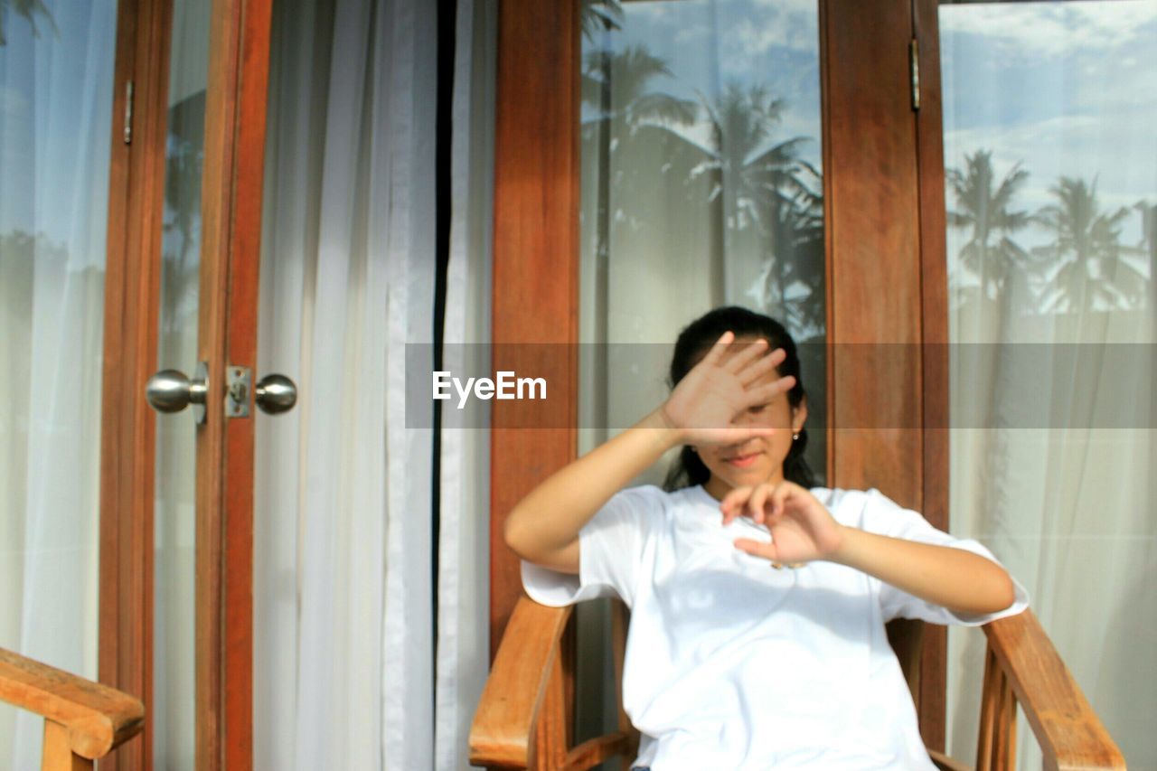 YOUNG WOMAN LOOKING THROUGH OPEN DOOR