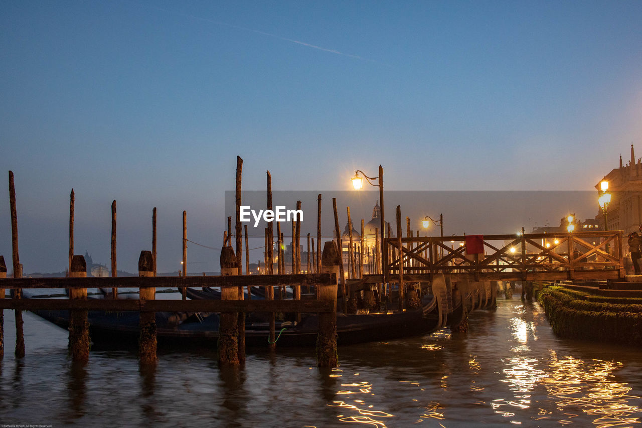 water, evening, reflection, transportation, nautical vessel, sky, dusk, architecture, nature, sea, mode of transportation, sunset, travel destinations, dock, boat, travel, no people, cityscape, built structure, city, twilight, illuminated, night, pier, vehicle, tranquility, ship, outdoors, harbor, beauty in nature, building exterior, scenics - nature, wood, moored, marina, tourism, waterway, landscape, gondola, clear sky, environment