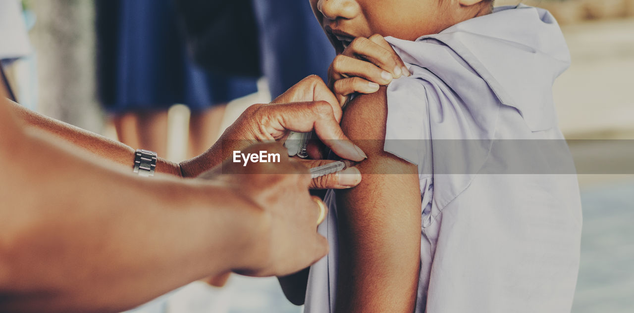 Cropped image of doctor injecting syringe to boy