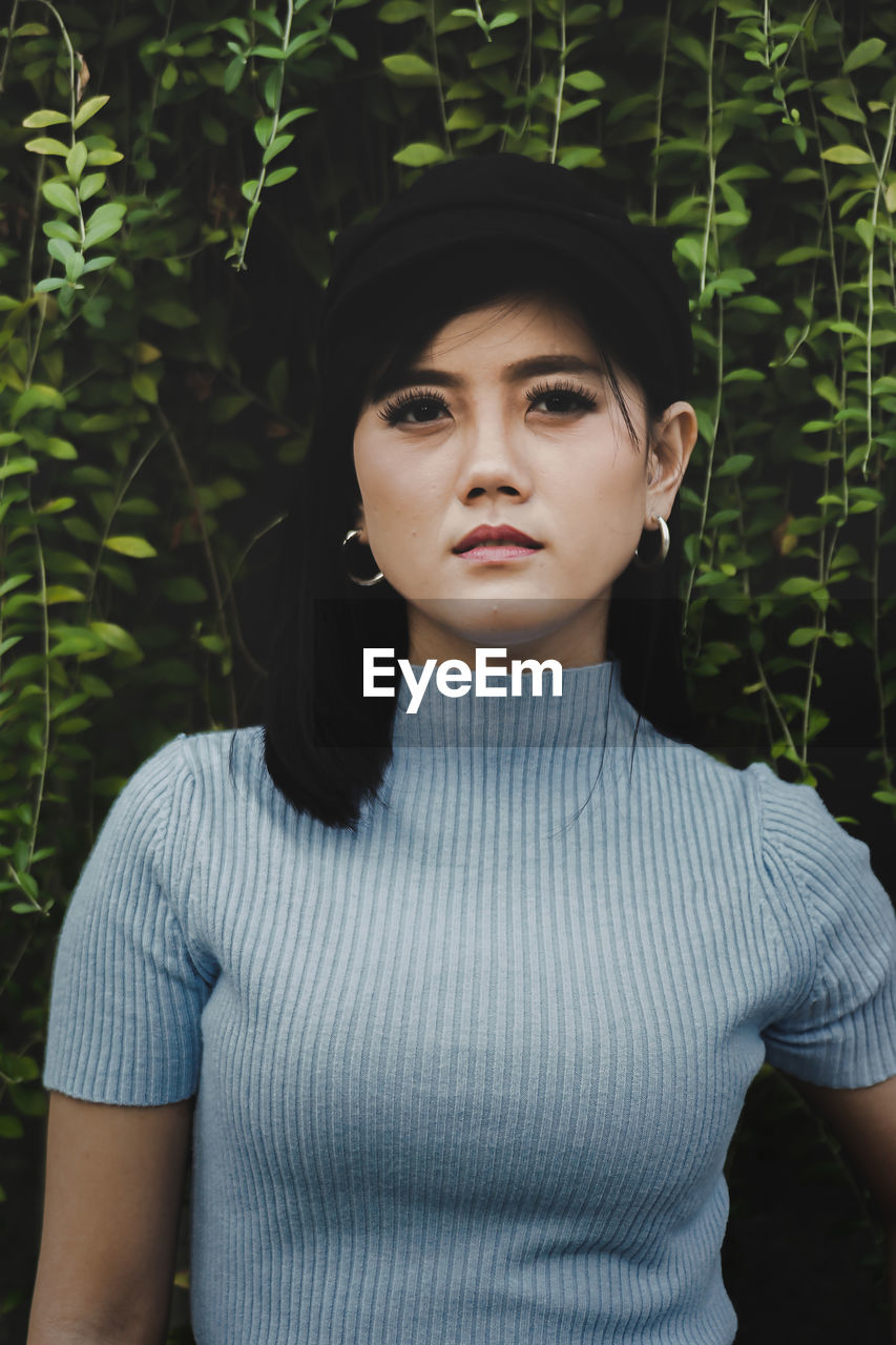 Portrait of beautiful woman standing against plants