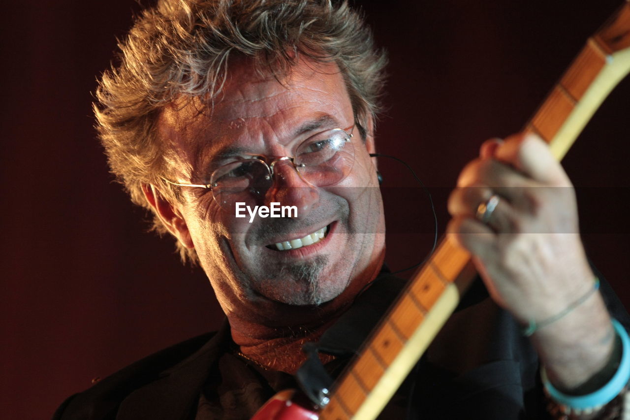 Close-up of smiling man playing guitar