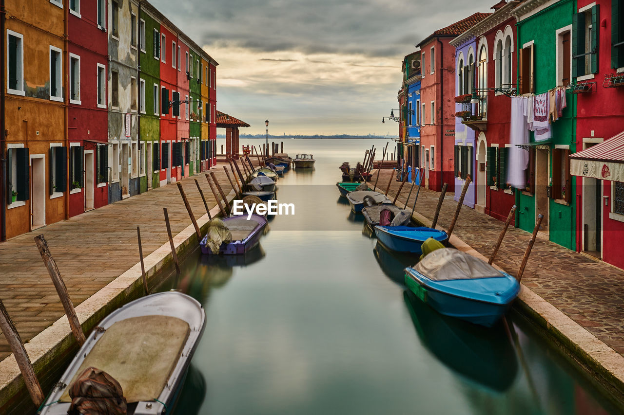 Boats moored in canal against sky