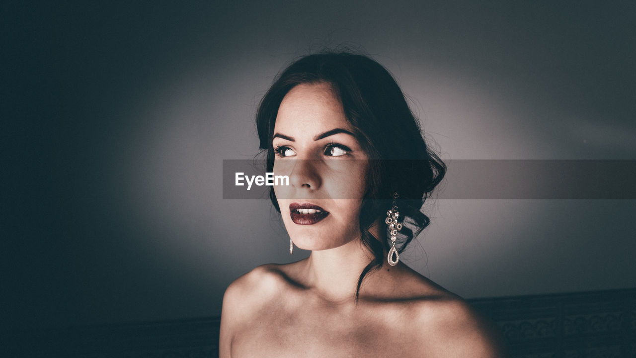 Young woman wearing lipstick and earrings at home