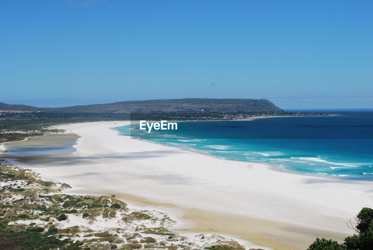 Scenic view of beach against clear blue sky