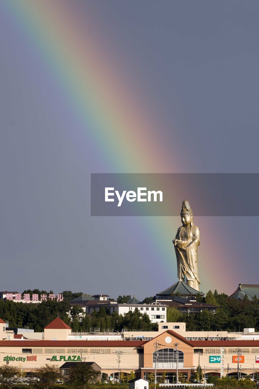 Statue of rainbow over building against sky