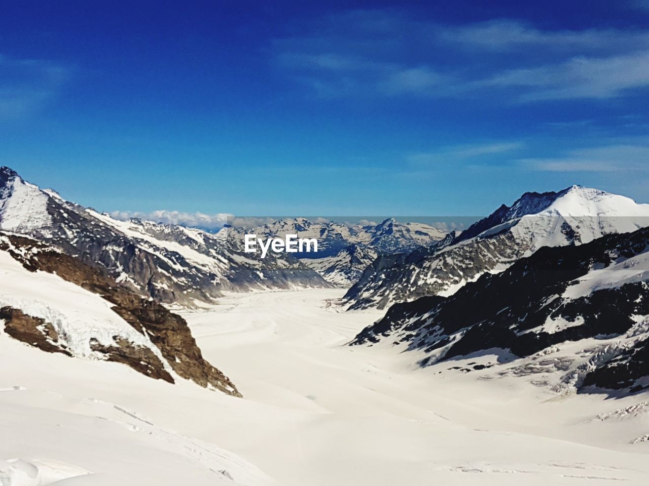 Scenic view of snowcapped mountains against blue sky