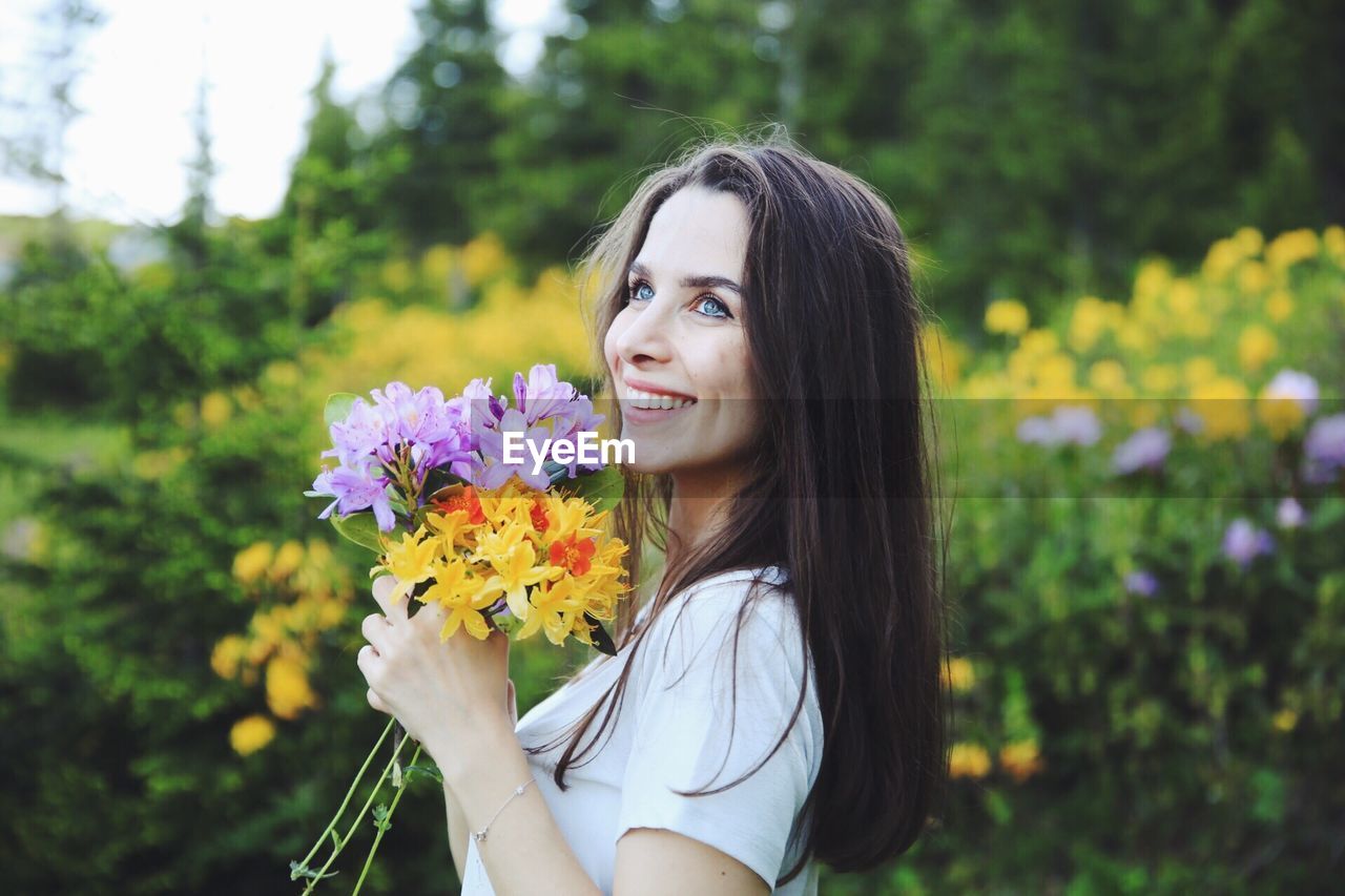 Beautiful woman looking away while holding flowers