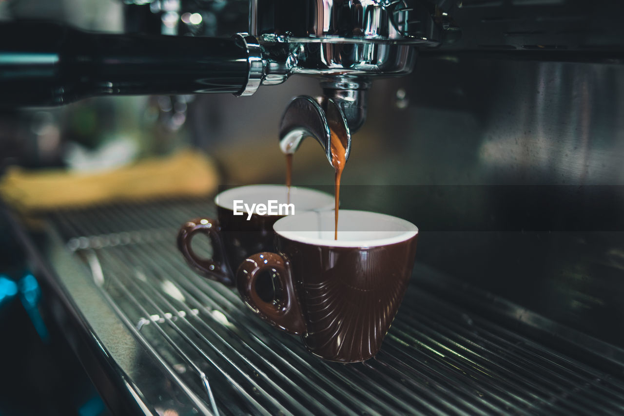 Close-up of coffee cup on espresso maker in cafe