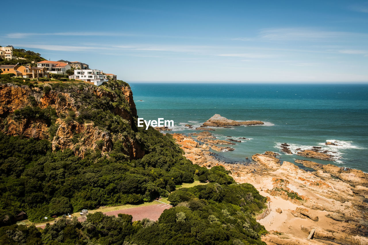 Scenic view of sea by cliff against sky