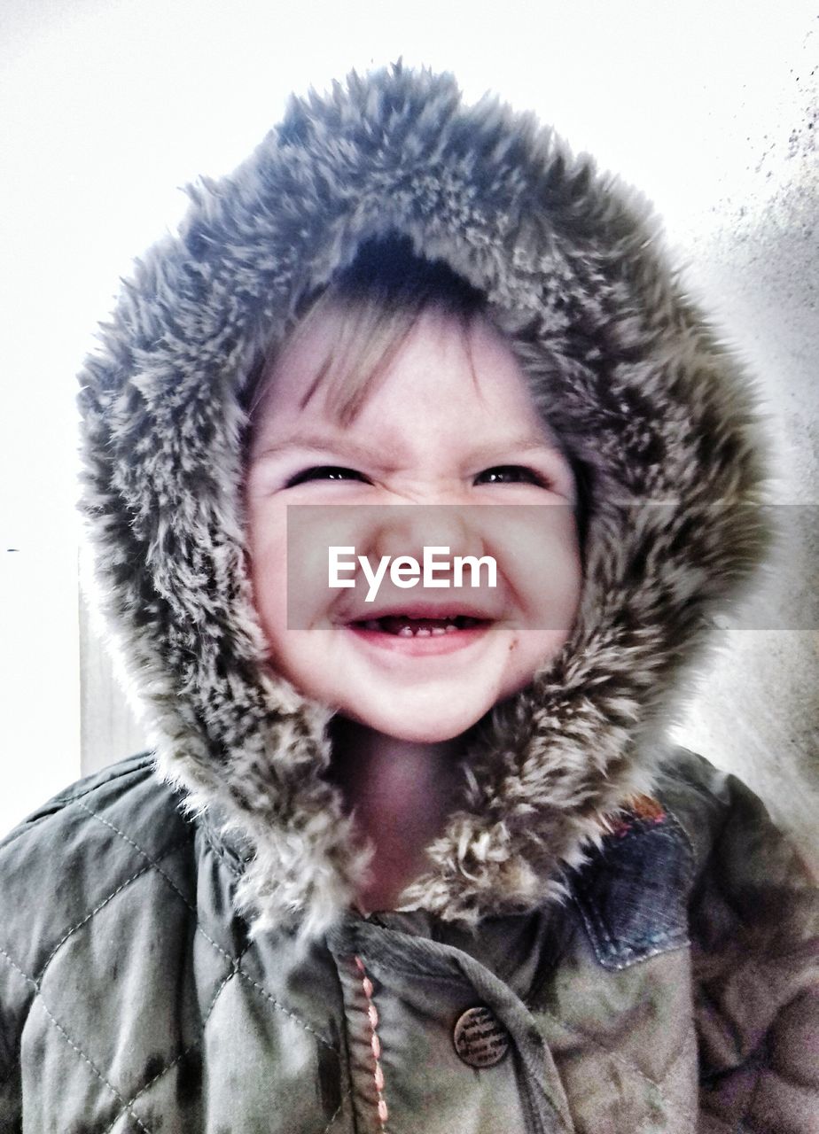 Close-up of cute toddler making face while wearing fur coat