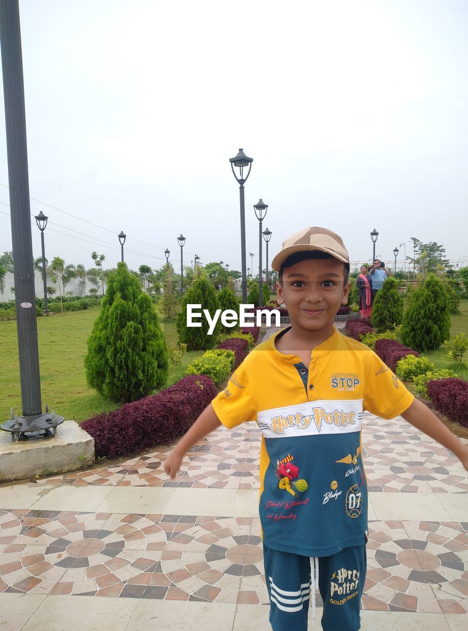 childhood, child, looking at camera, one person, portrait, men, smiling, front view, standing, day, happiness, architecture, emotion, nature, full length, pride, footpath, clothing, outdoors, sky, vacation, lifestyles, holding, cheerful