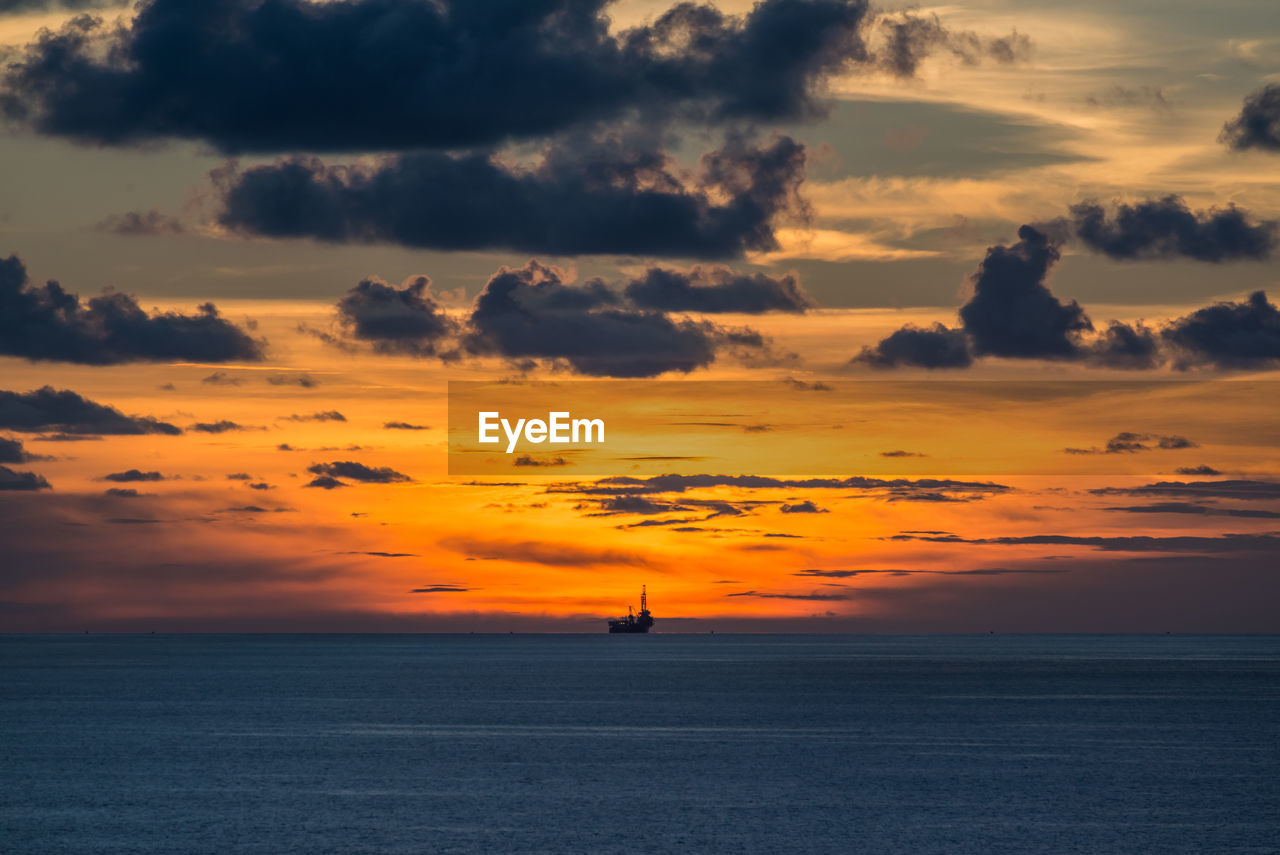 Scenic view of sea against cloudy sky during sunset