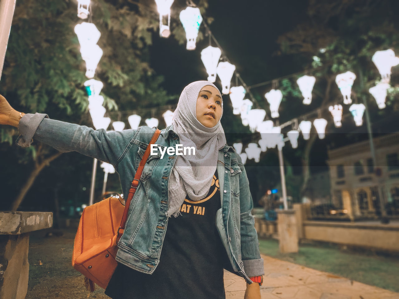 Woman standing against illuminated lights at night