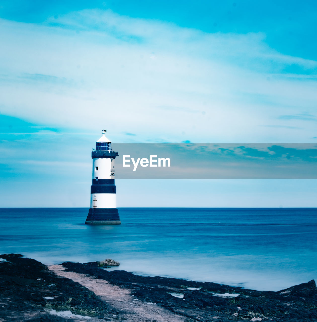 Lighthouse by sea against sky