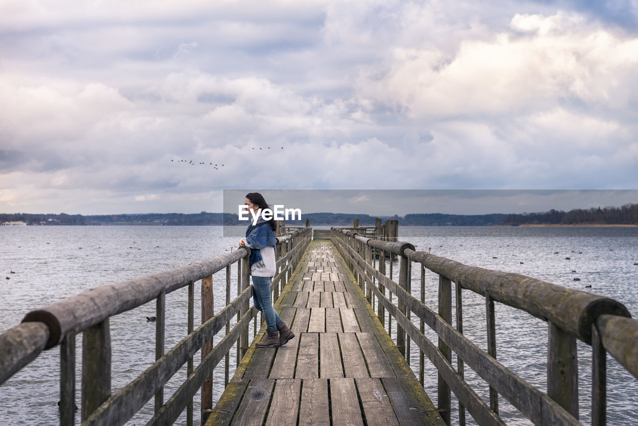 MAN STANDING ON PIER OVER SEA