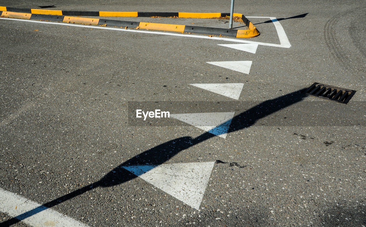 HIGH ANGLE VIEW OF ARROW SIGN ON ROAD