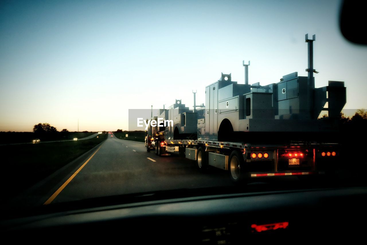 Tanker seen through car windshield against clear sky at dusk