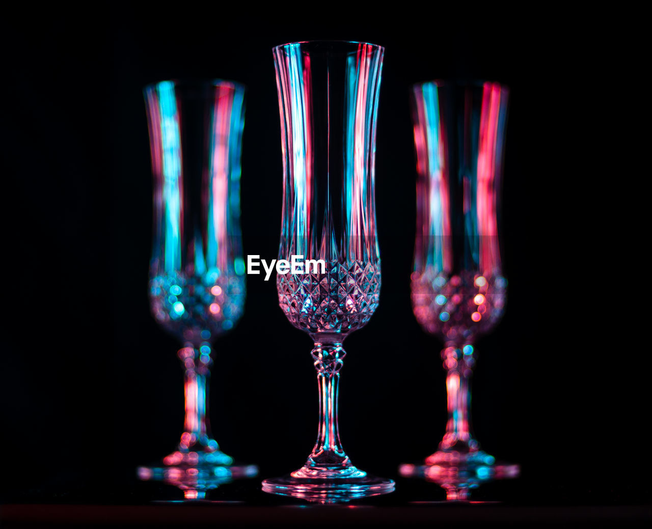Close-up of wine glasses on table against black background