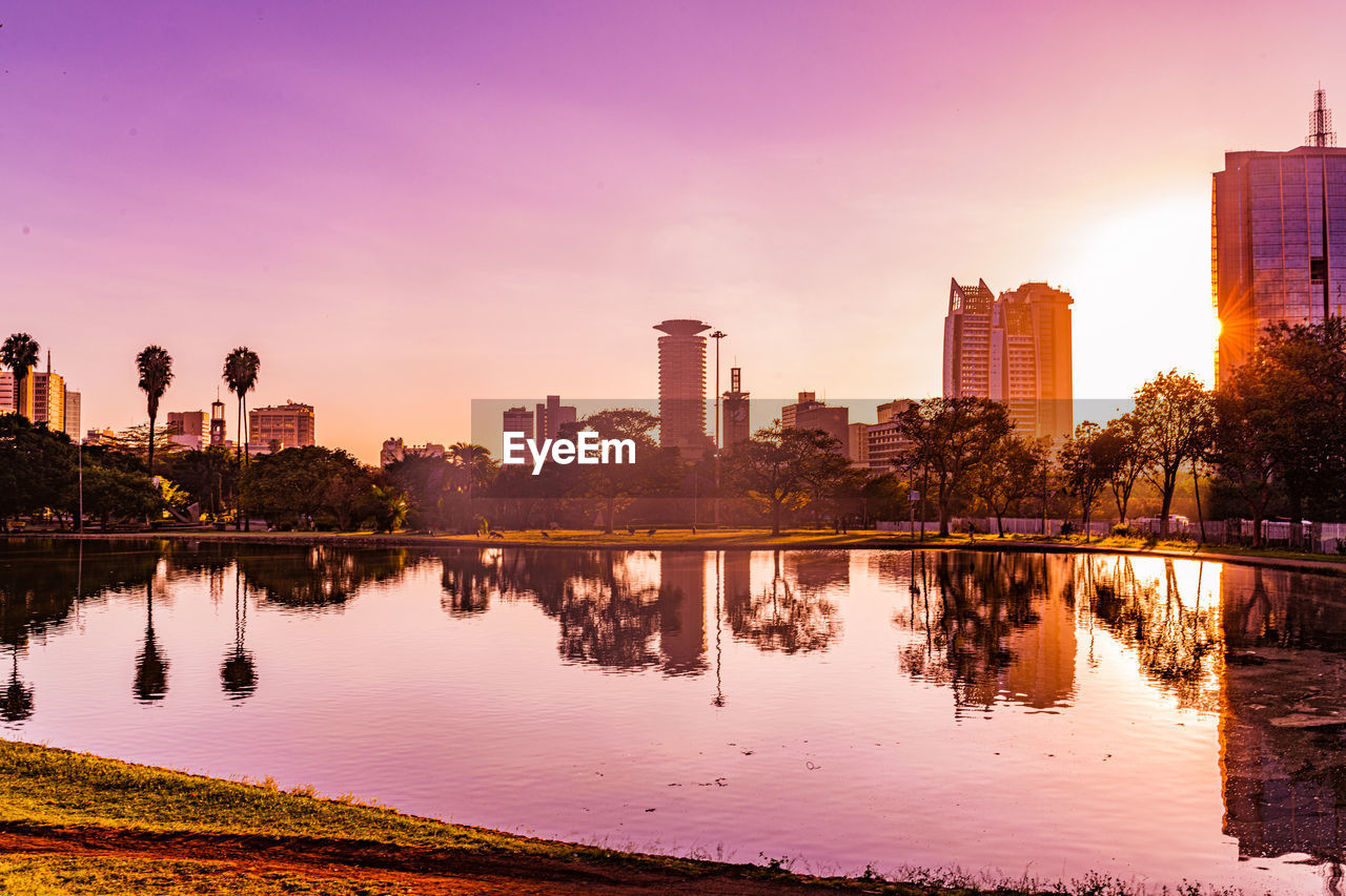 city, architecture, reflection, skyline, landscape, water, building exterior, built structure, sky, sunset, dusk, building, urban skyline, cityscape, evening, office building exterior, skyscraper, nature, horizon, travel destinations, downtown district, twilight, residential district, lake, city life, environment, sun, travel, outdoors, business finance and industry, beauty in nature, cloud, scenics - nature, multi colored, illuminated, pink, no people, tranquility, business, transportation, office, panoramic