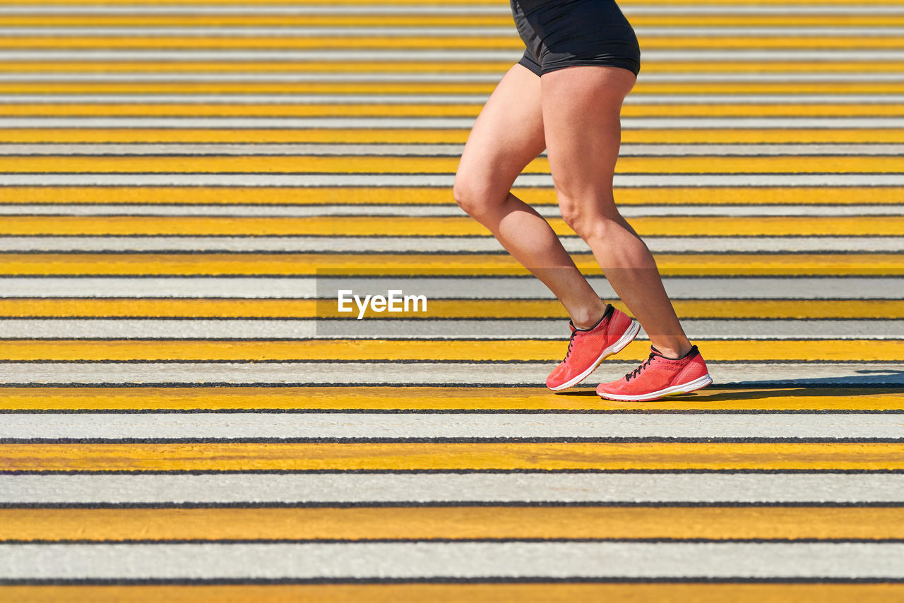 Woman running crosswalk, copy space. athletic woman jogging in sportswear on city road