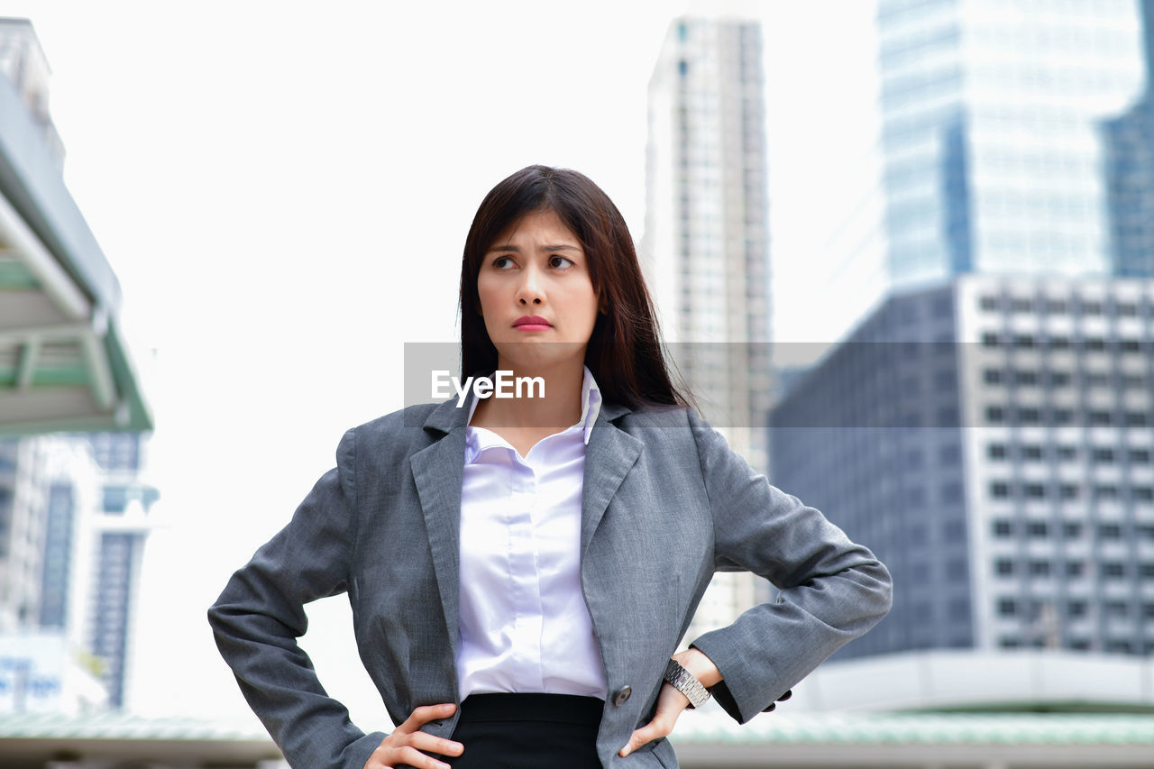 Worried businesswoman with hands on hip standing in city