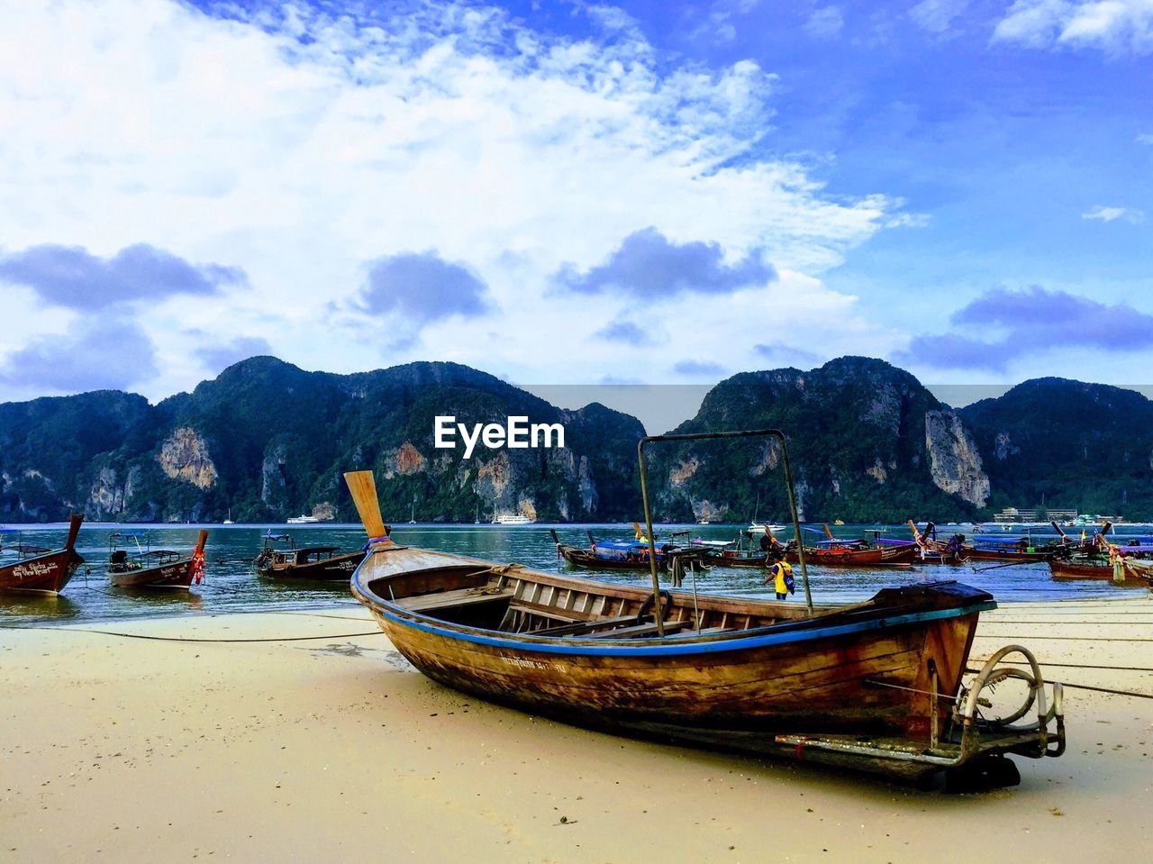BOATS MOORED IN SEA AGAINST MOUNTAINS