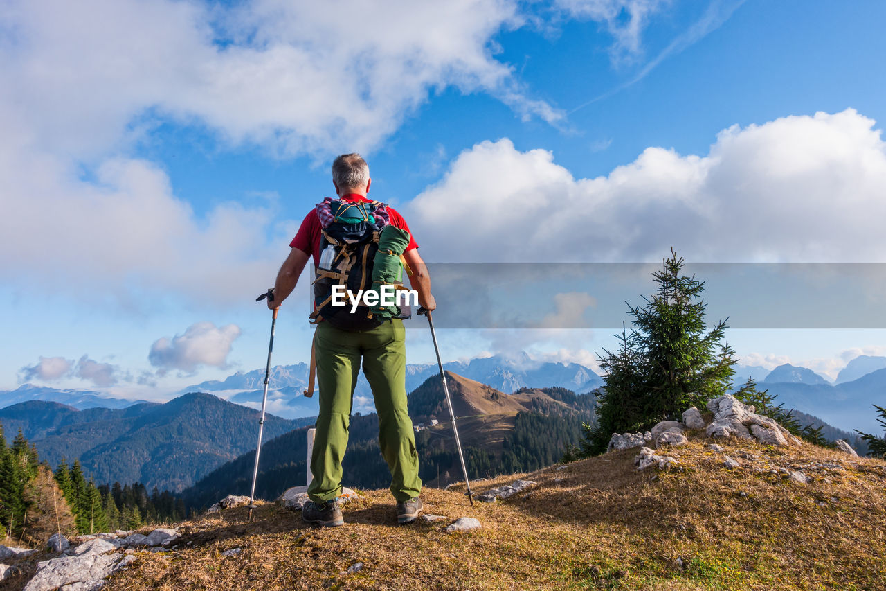 Rear view of backpacker with hiking poles looking at mountains