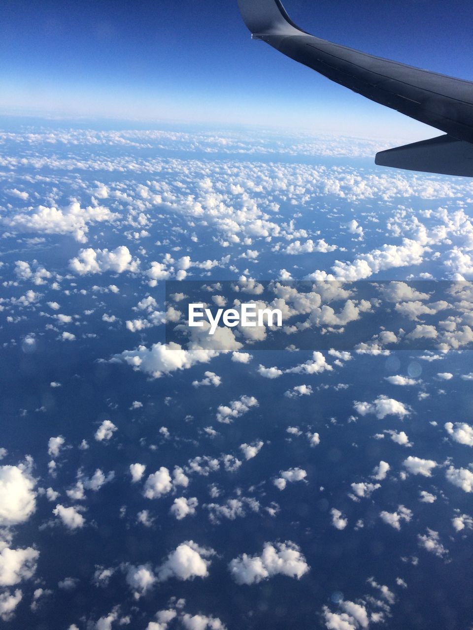 AERIAL VIEW OF CLOUDS OVER LANDSCAPE SEEN THROUGH AIRPLANE