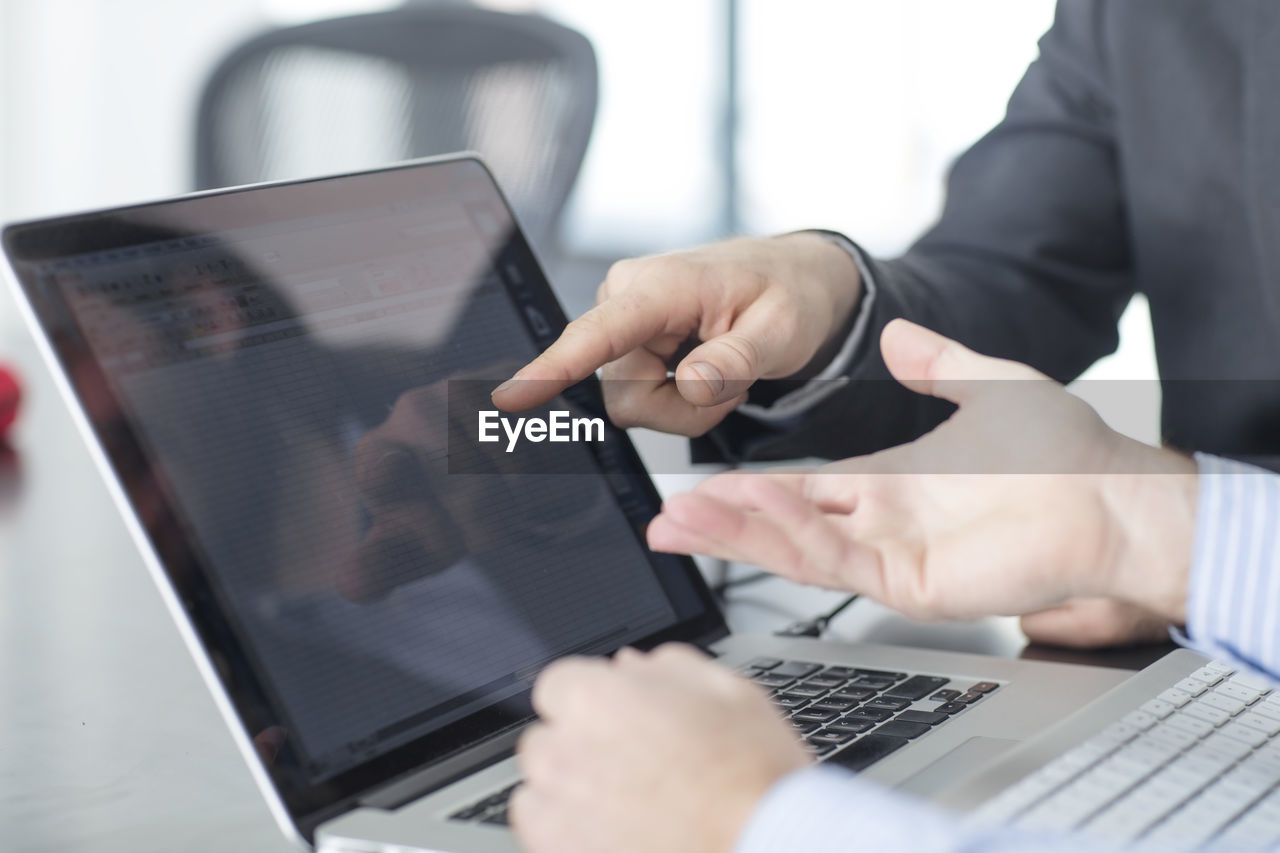 Colleagues in office pointing at laptop screen