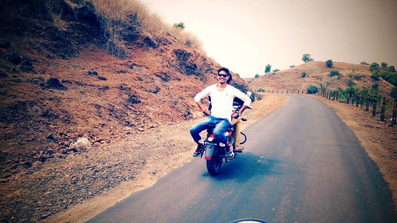 REAR VIEW OF PEOPLE RIDING MOTORCYCLE ON ROAD