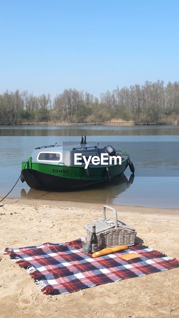 BOATS MOORED ON SHORE AGAINST SKY