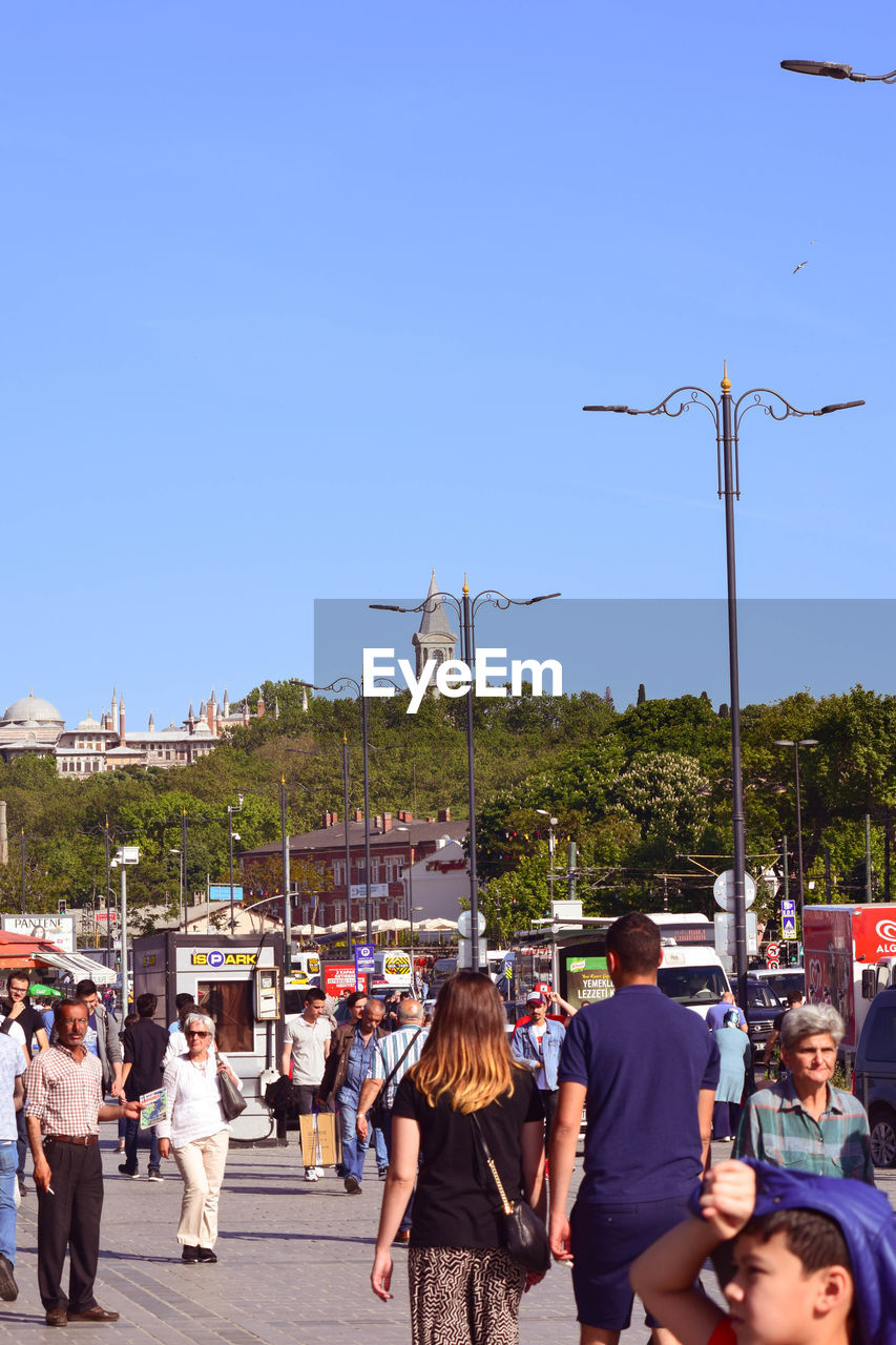 PEOPLE ON STREET AGAINST BLUE SKY