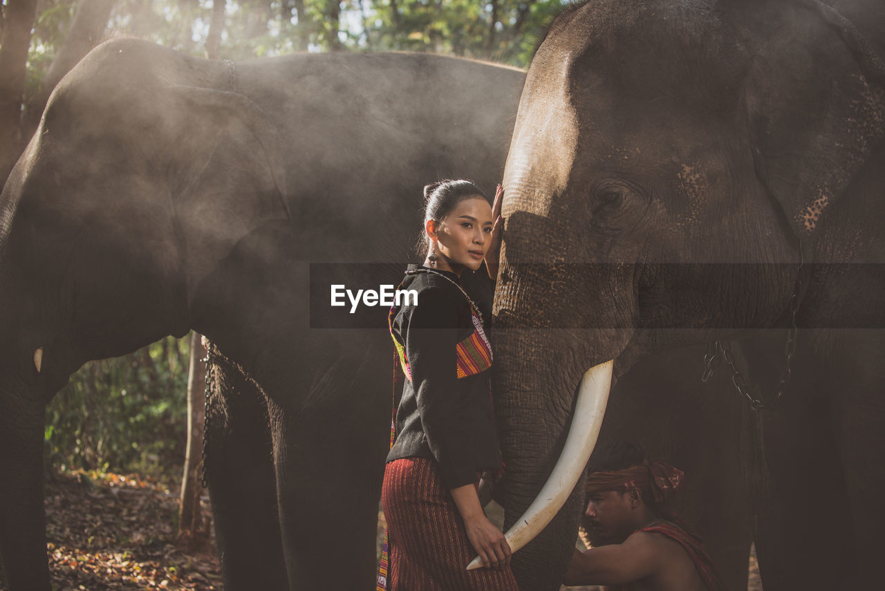 Portrait of smiling woman standing with elephant in temple