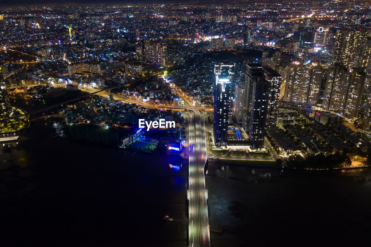 HIGH ANGLE VIEW OF ILLUMINATED CITY STREET AND BUILDINGS AT NIGHT