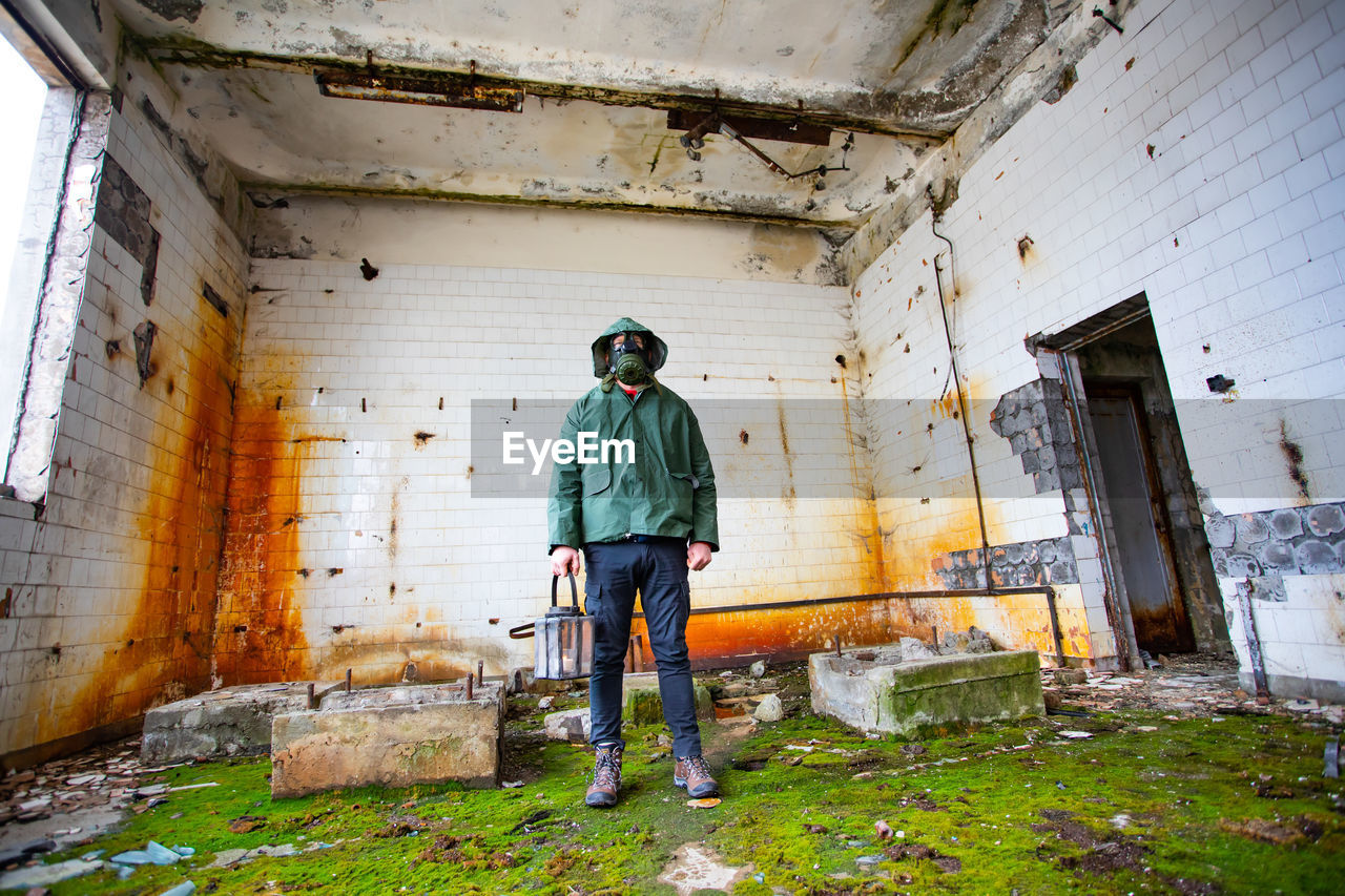 MAN STANDING ON ABANDONED BUILDING