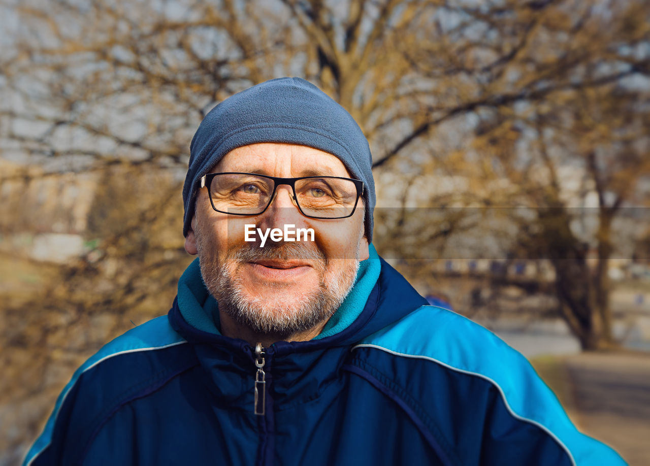 Close-up of man in eyeglasses looking away at park