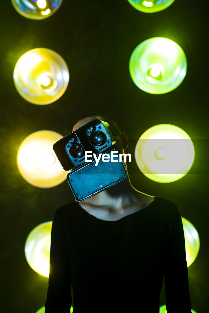 Woman with head cocked wearing vr glasses in front of neon lighting