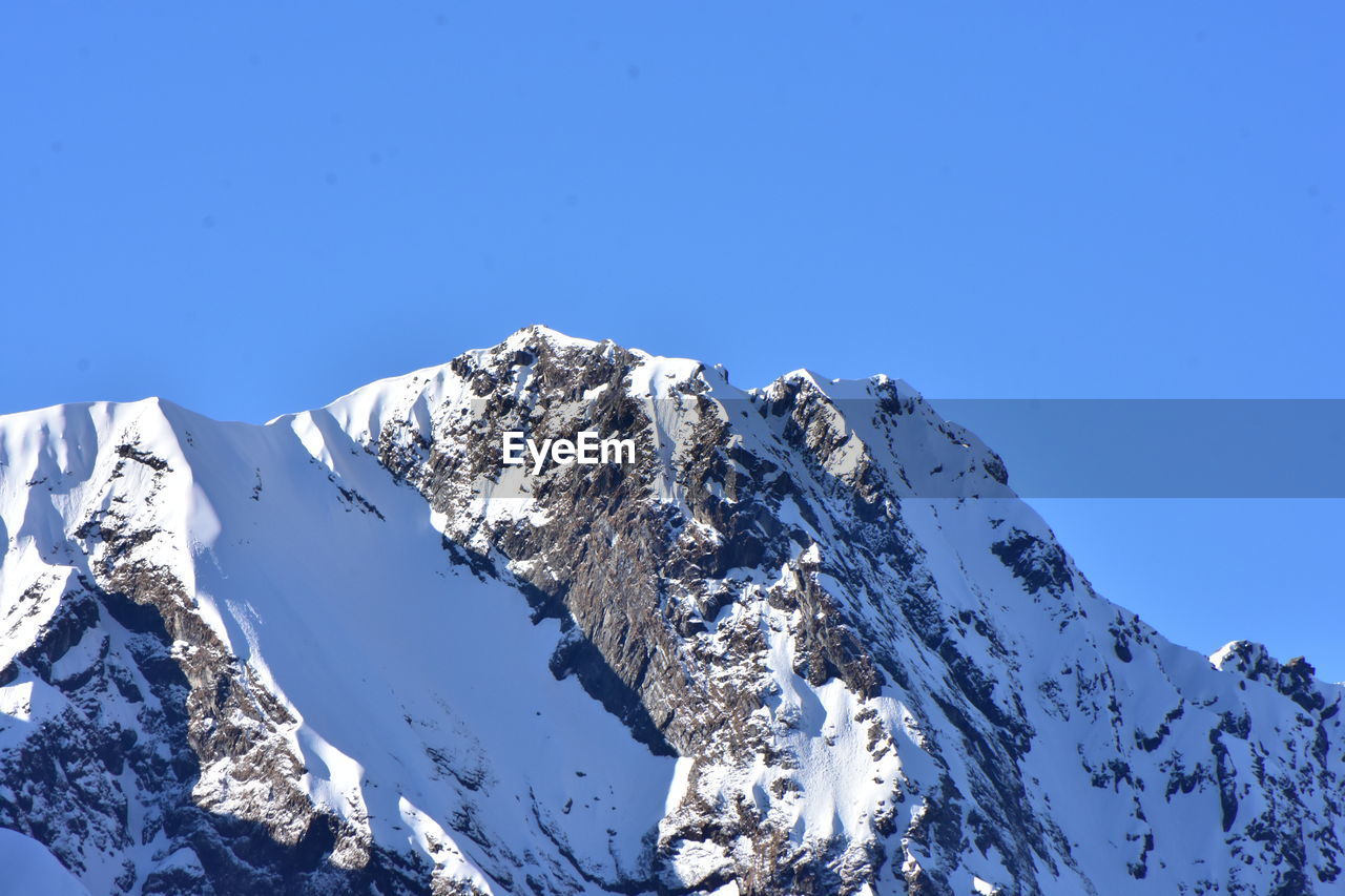 Scenic view of snowcapped mountains against clear blue sky