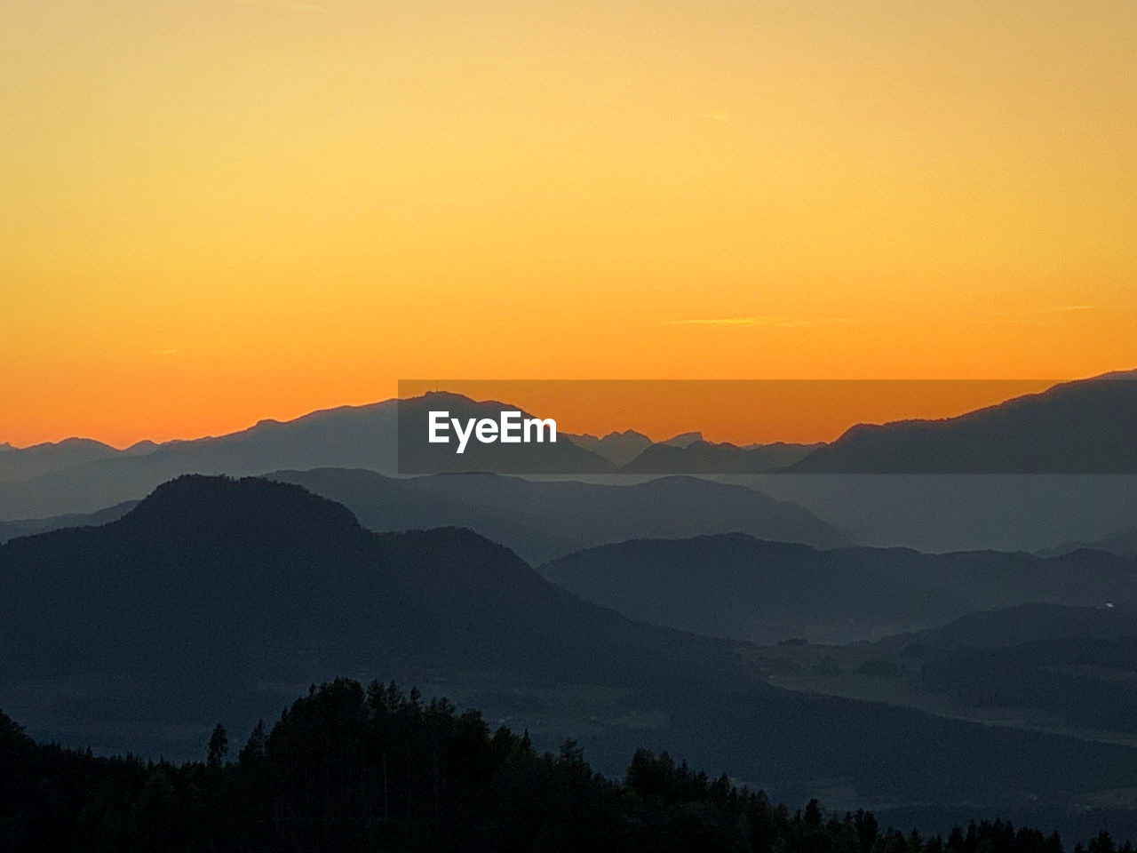 Scenic view of silhouette mountains against orange sky