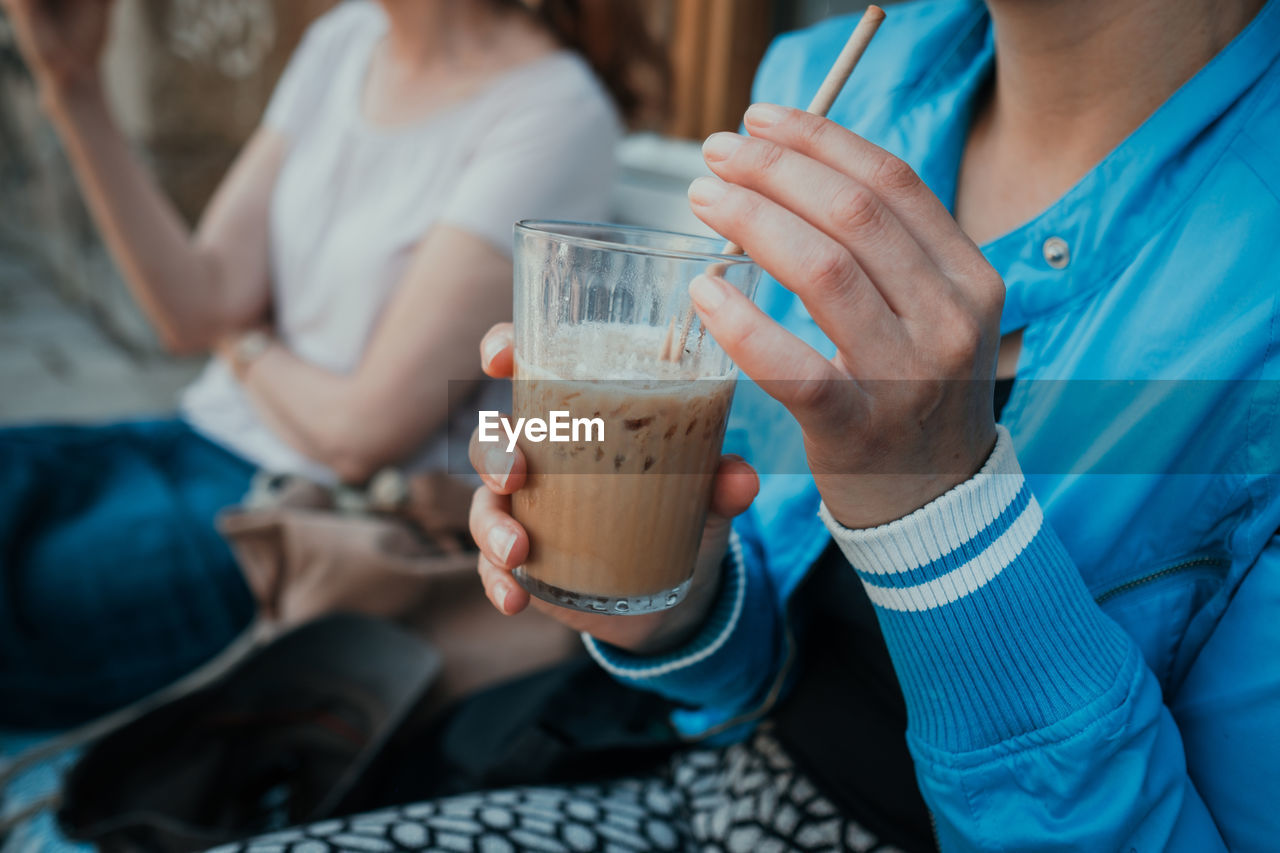 Midsection of woman holding iced coffee