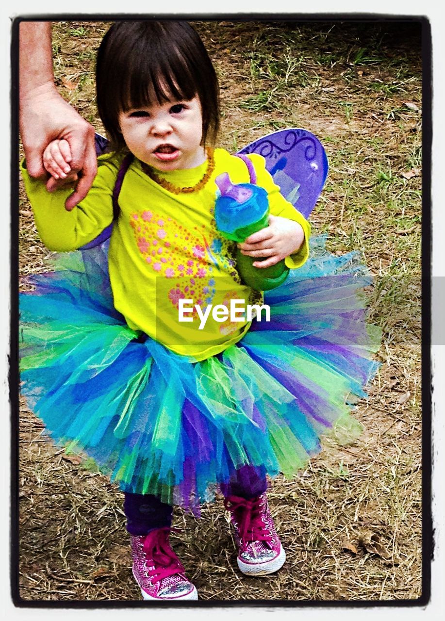 Portrait of cute girl in fairy costume holding father hand in park